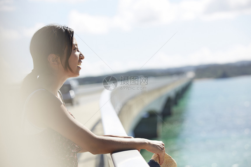 旅途中的女性走在海面大桥上看风景图片