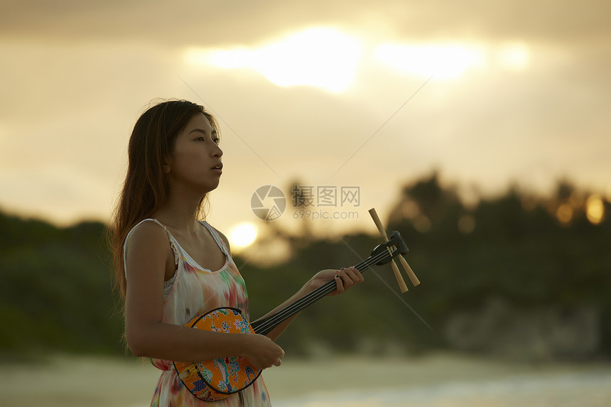  夕阳下弹乐器的女性图片