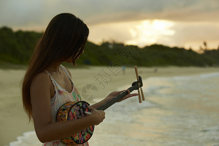  夕阳下弹乐器的女性图片