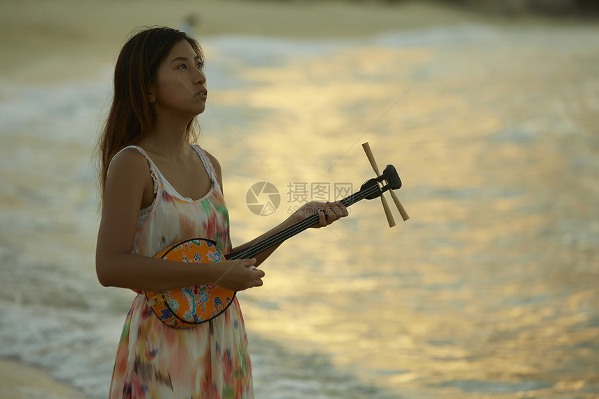 夕阳下弹乐器的女性图片