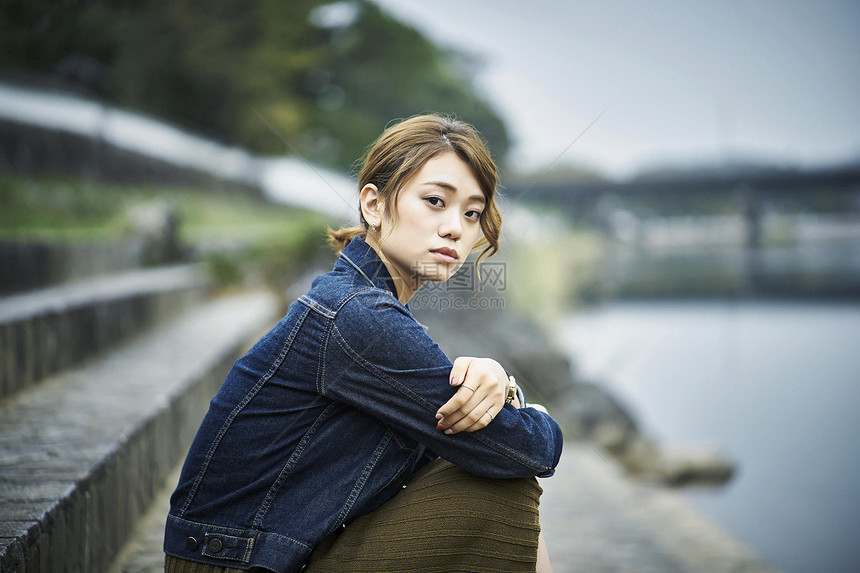 坐在河堤上的年轻女性图片