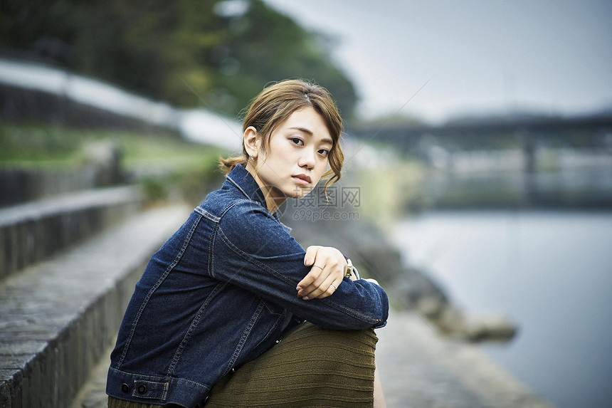 坐在河堤上的年轻女性图片