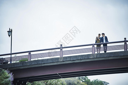 站在桥上拍照的年轻情侣图片