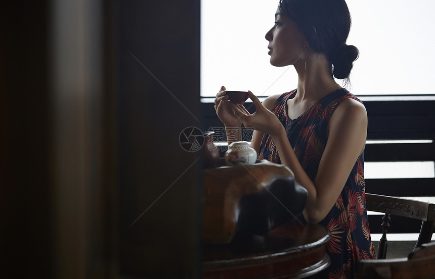 女人在茶馆窗台边品茶看窗外图片