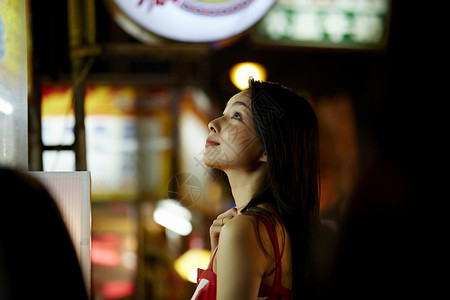 在夜市逛街的女游客抬头看图片