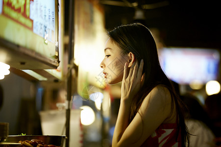 在夜市逛街的女游客摸头发图片