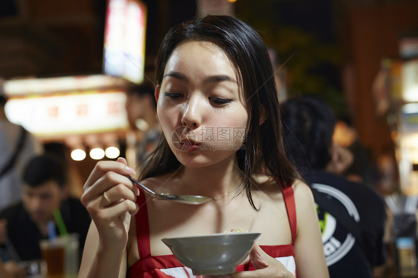 在夜市逛街的女游客吃小吃图片