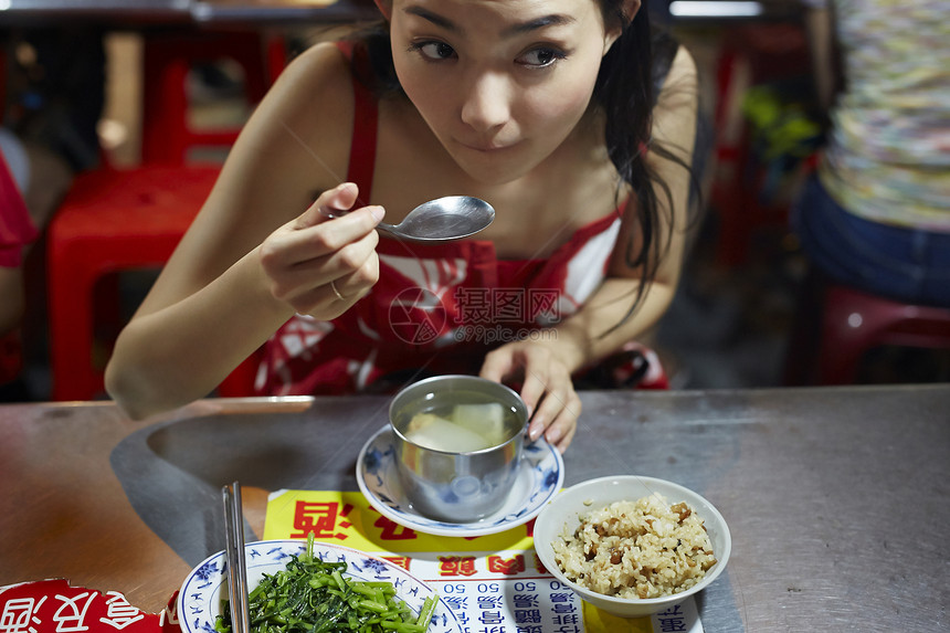 在夜市逛街的女游客吃小吃图片