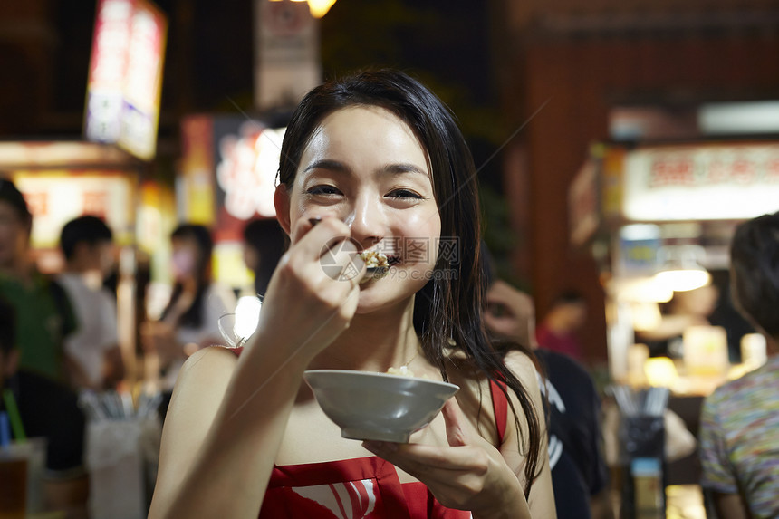 在夜市逛街的女游客吃小吃图片