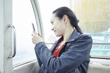 在游乐园摩天轮上的女人拿手机拍窗外图片