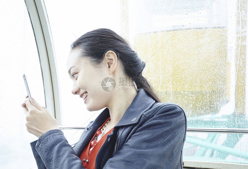 在游乐园摩天轮上的女人拿手机拍窗外图片