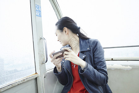 在游乐园摩天轮上的女人拿着手机看窗外图片