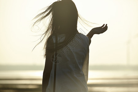 日落时女人站在湿地撩头发的剪影背景图片