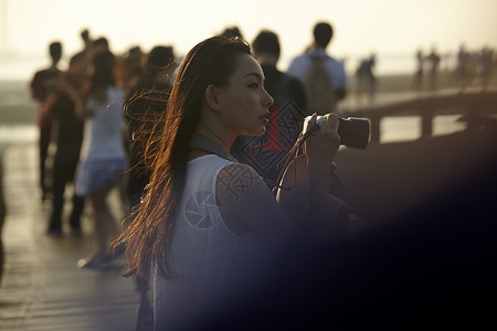 日落时在湿地拿着相机的女人图片