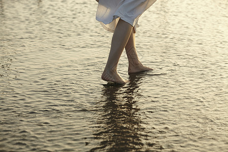 日落时女人站在湿地的脚背景图片
