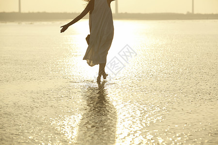 日落时分走在海滩边上长裙美女背景图片