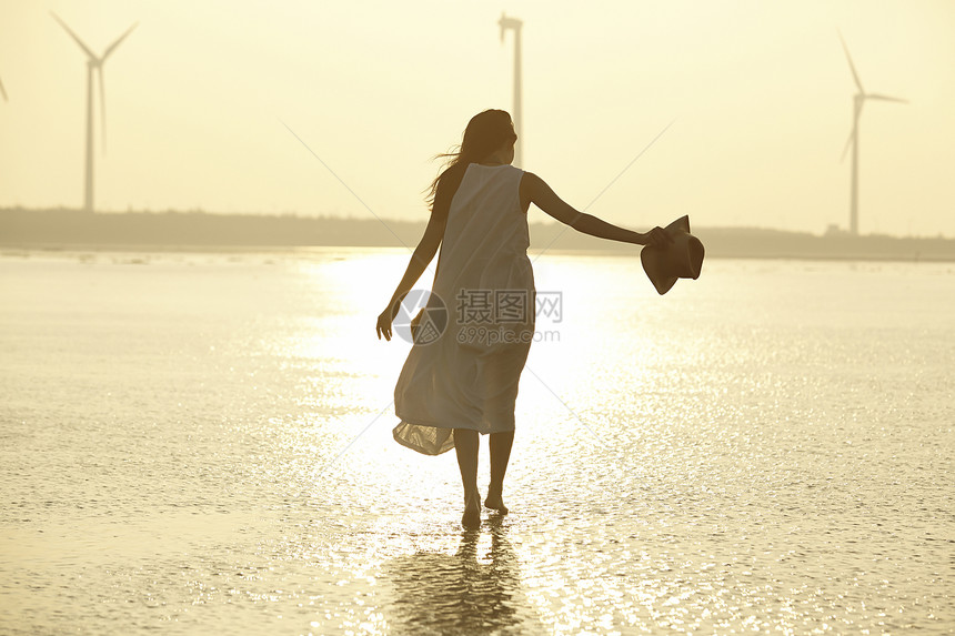 日落时分走在海滩边上长裙美女图片
