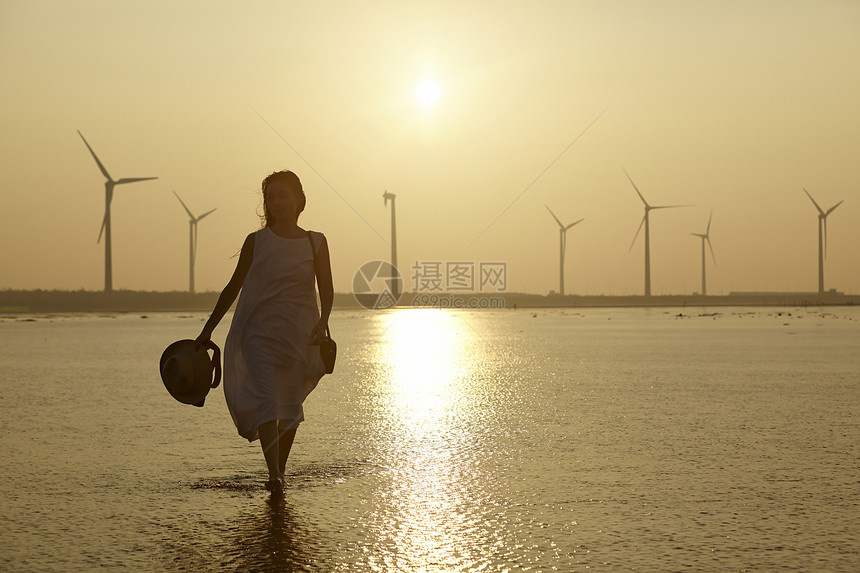 日落时分走在海滩边上长裙美女图片