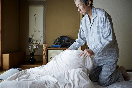 独居老人在叠被褥背景图片