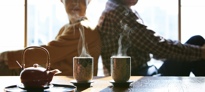 茶意人生背靠背坐在起居室茶桌旁的老夫妻背景