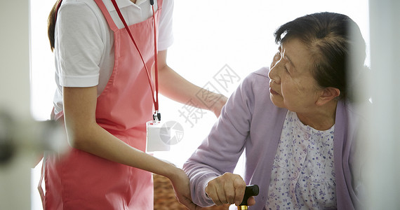 专业护理员扶着拄拐杖的独居老妇人图片