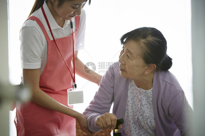 专业护理员扶着拄拐杖的独居老妇人图片