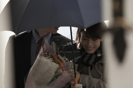 女孩牵着打着伞拿着花的男友上楼背景图片