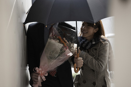 女人看着拿着伞和花束的男人微笑图片