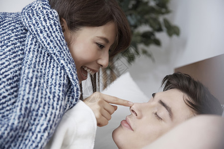 床上女人笑着摸男人的鼻子背景图片
