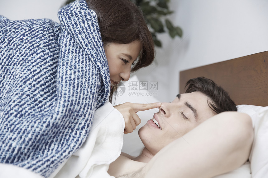 床上女人笑着摸男人的鼻子图片