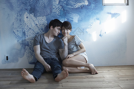 蓝色墙壁前坐着的情侣图片
