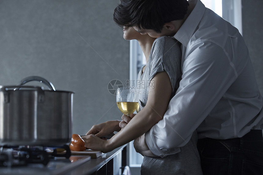 端着酒杯的男人搂着切菜的女人图片