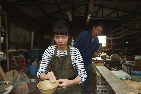 陶瓷师傅指导体验陶瓷制作的女人图片