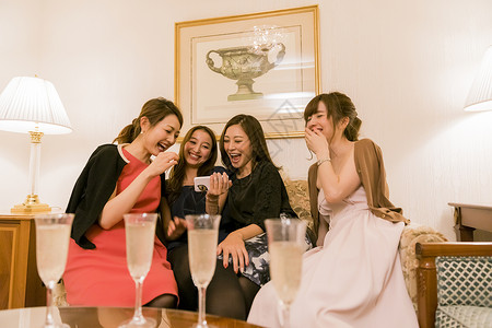朋友聚会女人们在桌边说笑看手机图片