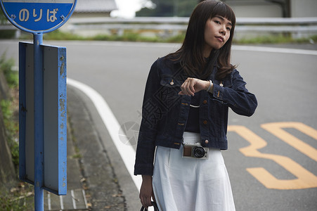 女子路边看时间等车
图片