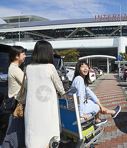 在机场停车场推着行李和朋友走的女人图片
