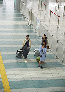 机场航站楼里拖着行李准备乘坐飞机的三名女性图片