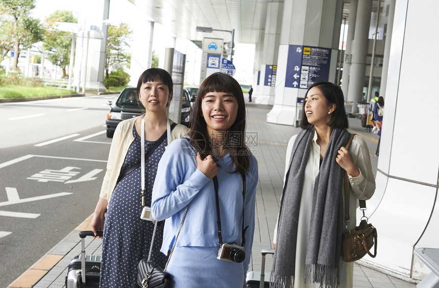 机场航站楼里拖着行李准备乘坐飞机的三名女性图片