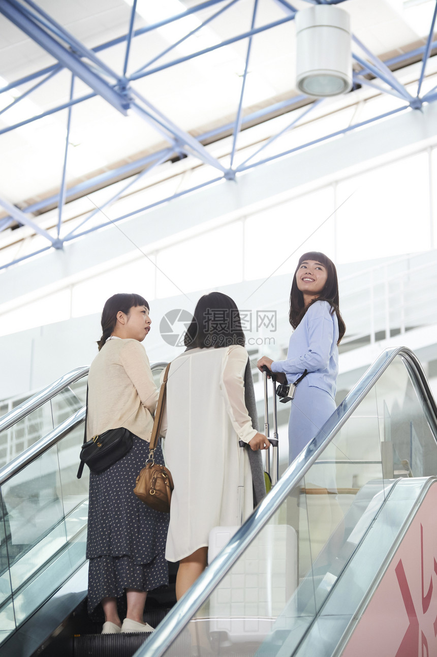 机场航站楼里拖着行李准备乘坐飞机的三名女性图片