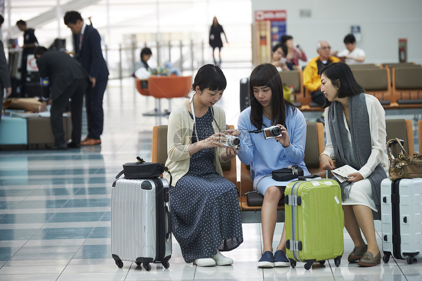 带着行李坐在航空站候车室的女人们图片