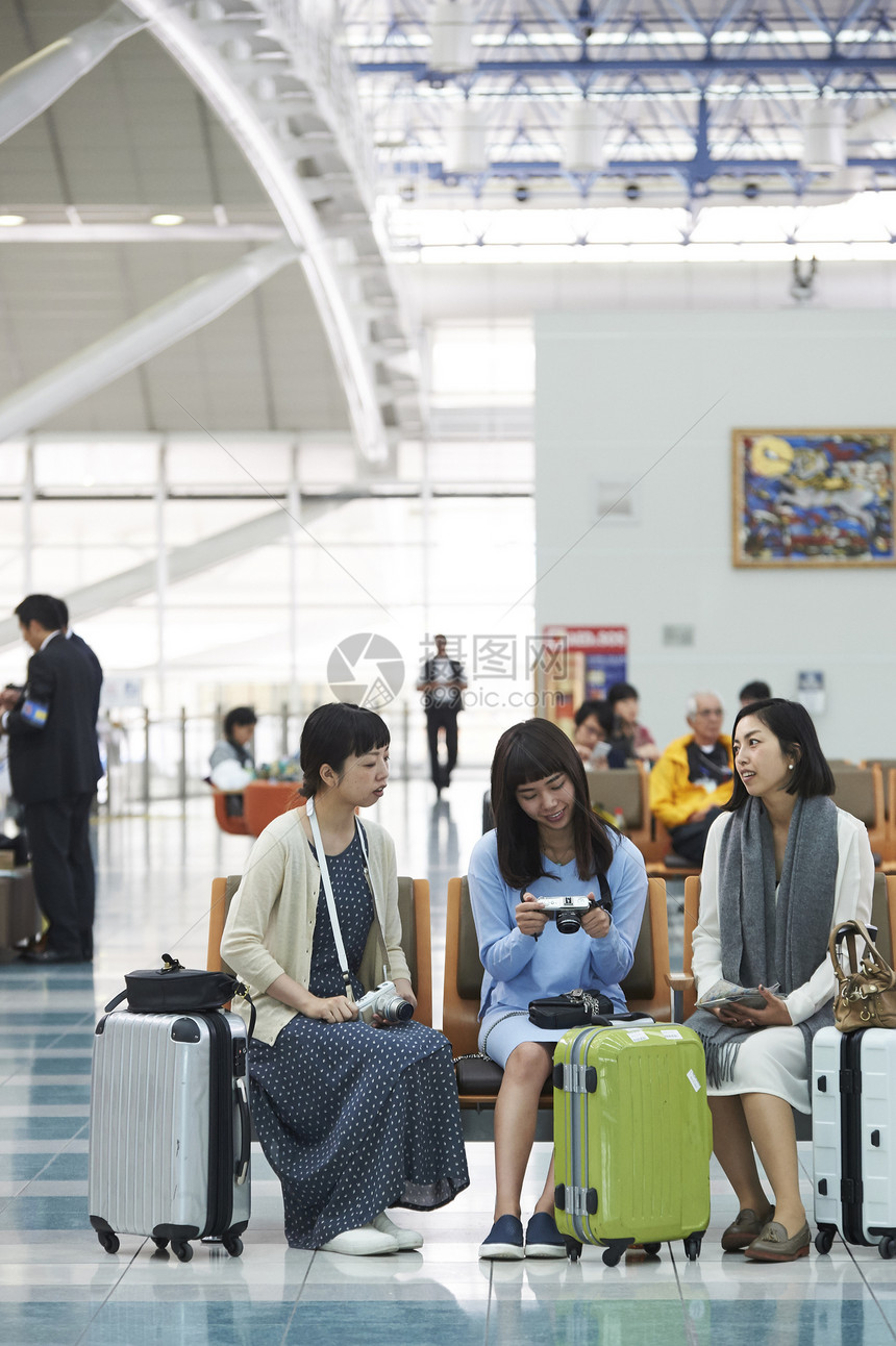 带着行李坐在航空站候车室的女人们图片