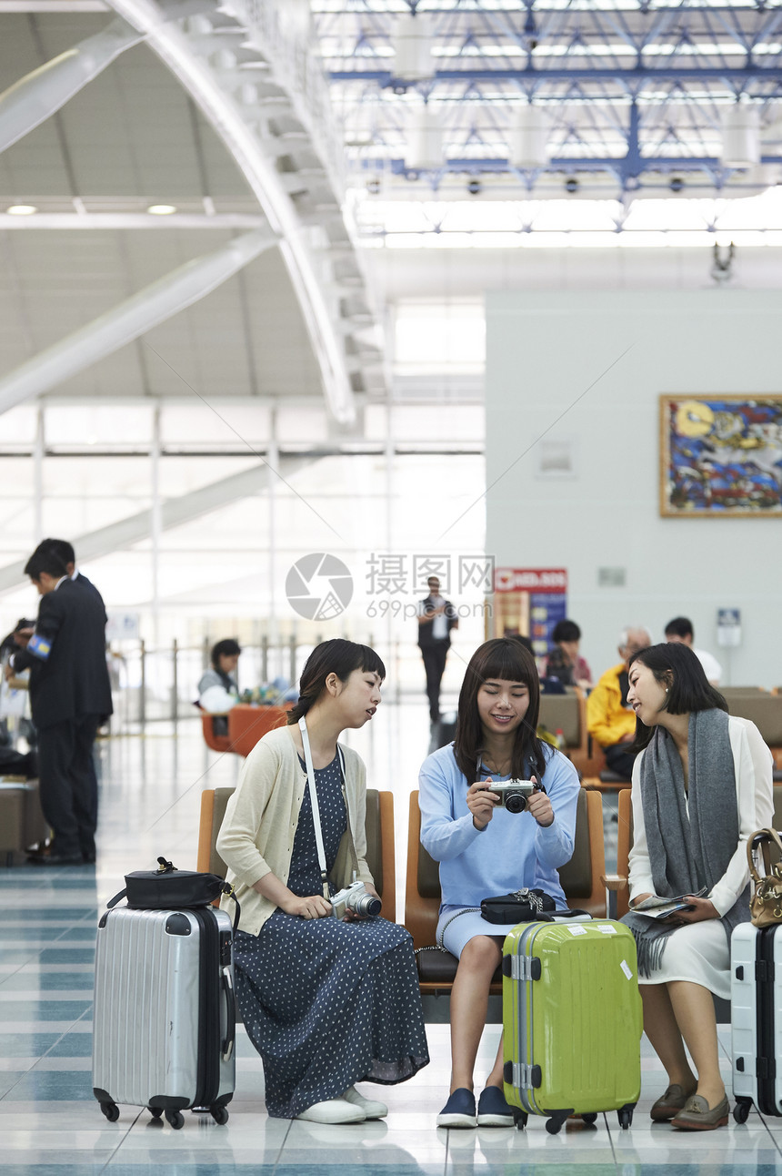 拿着行李坐在航空站候车室椅子上的女人们图片