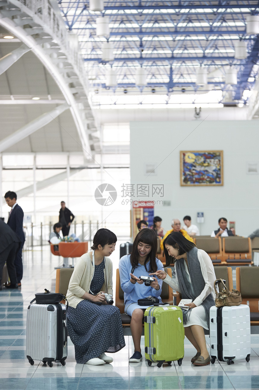 拿着行李坐在航空站候车室椅子上的女人们图片