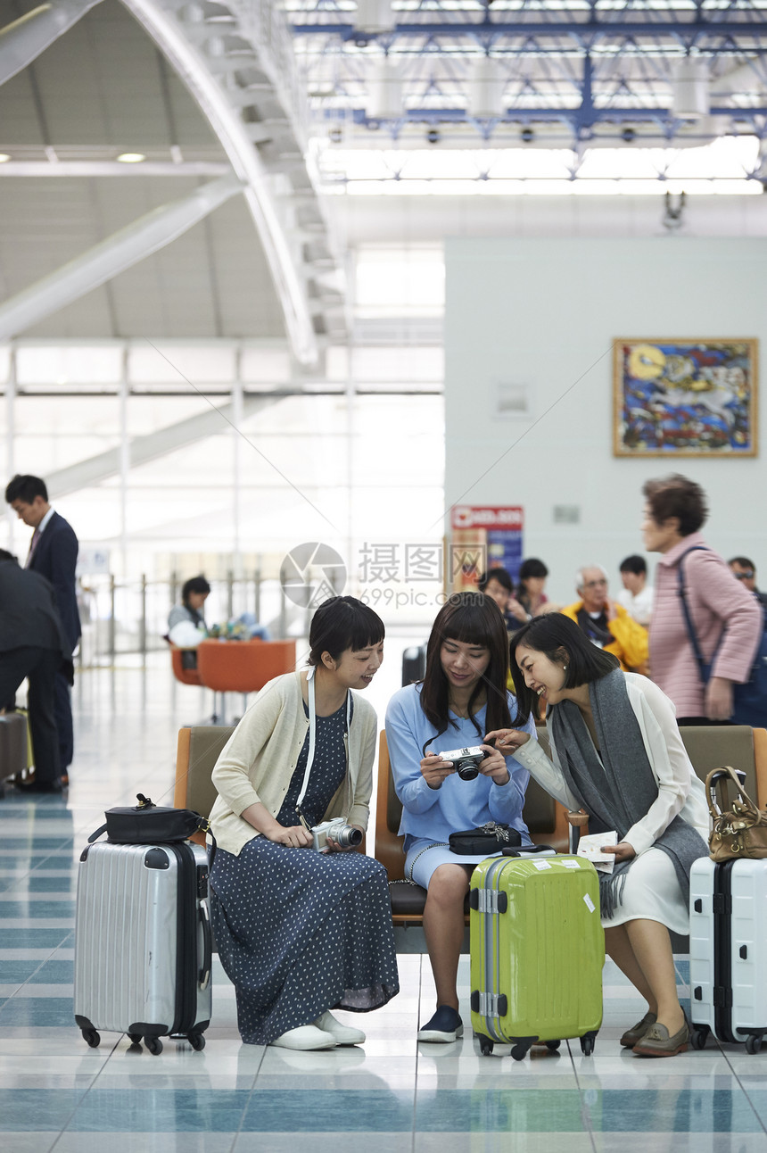 拿着行李坐在航空站候车室椅子上的女人们图片