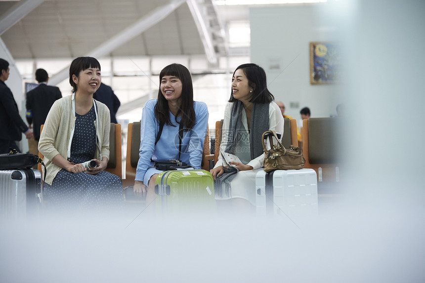 拿着行李坐在航空站候车室椅子上的女人们图片