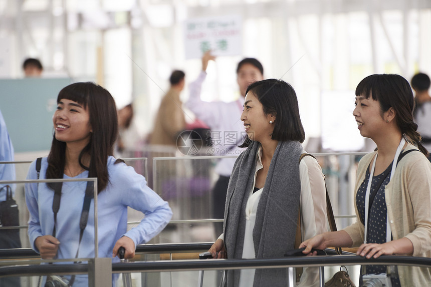 拿着行李走在航空站的女人们图片