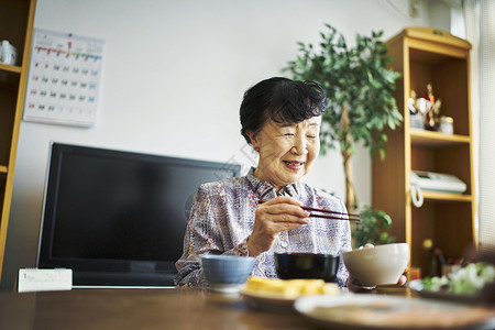 坐在家里吃饭的老妇人背景图片