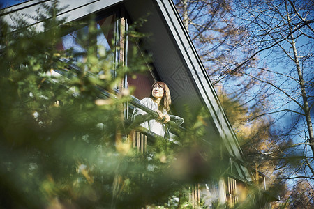 在森林度假别墅阳台远望的女人图片