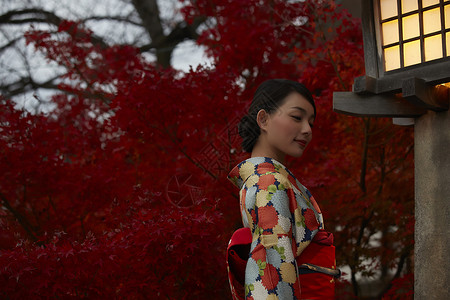 茶屋町穿着和服的女人站在枫叶前图片