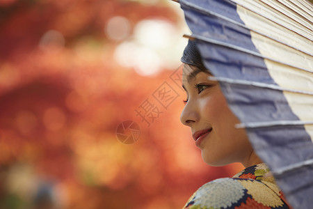 茶屋町穿着和服的女人拿着伞站在枫叶前图片